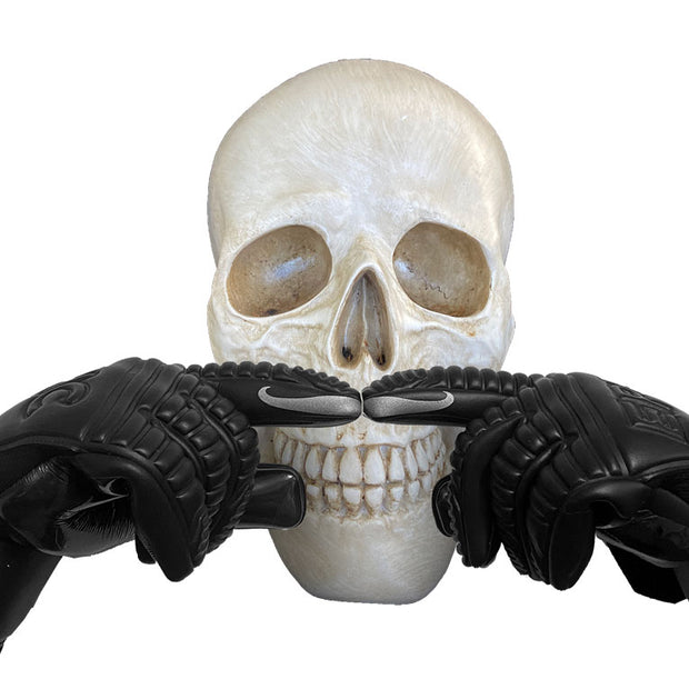 2 all black soccer goalkeeper gloves that have mustaches printed on the index finger tips. The mustache prints are being placed over a plastic skull to look like the skull has a mustache. These soccer goalie gloves are called the Glue Soccer Gloves and have 4mm of German contact latex on the palm. This picture is for Halloween to show off Halloween colors on soccer goalkeeper gloves by EPIC Soccer Academy. 